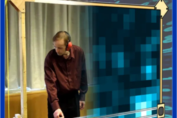 An instructor stands at a large square grid, demonstrating how to adjust the X and Y axis to draw out holograms in real time. 