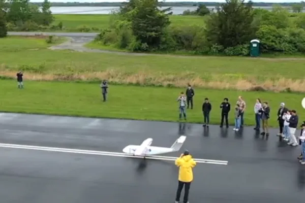 A 9-person class is shown testing their self-built small aircraft on a remote runway at Plum Island Airport.